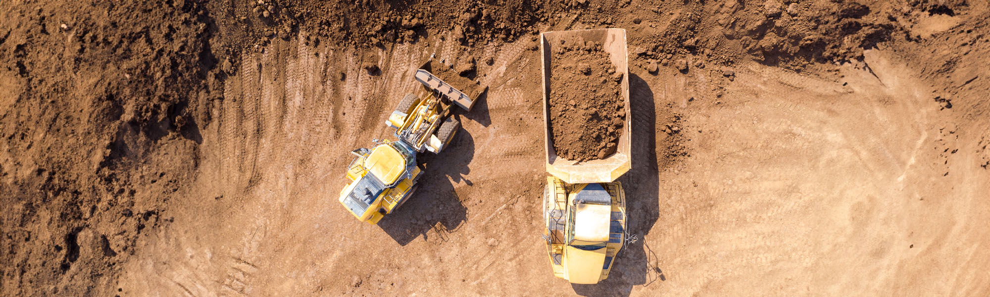 excavator loading soil onto an articulated hauler