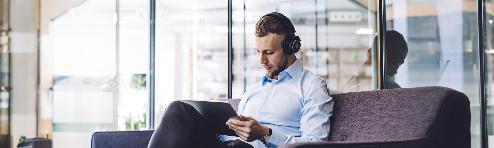 man with headphones sitting in office and using tablet